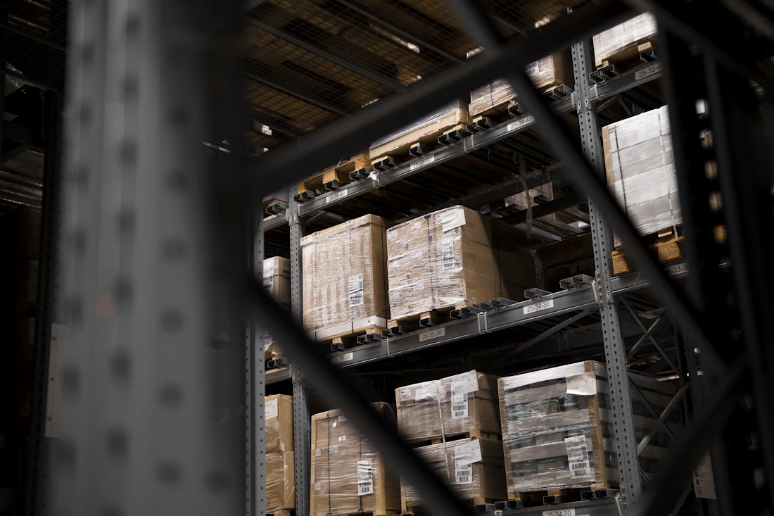 Shrink-wrapped pallets on steel racking, seen through the frame of the next bay